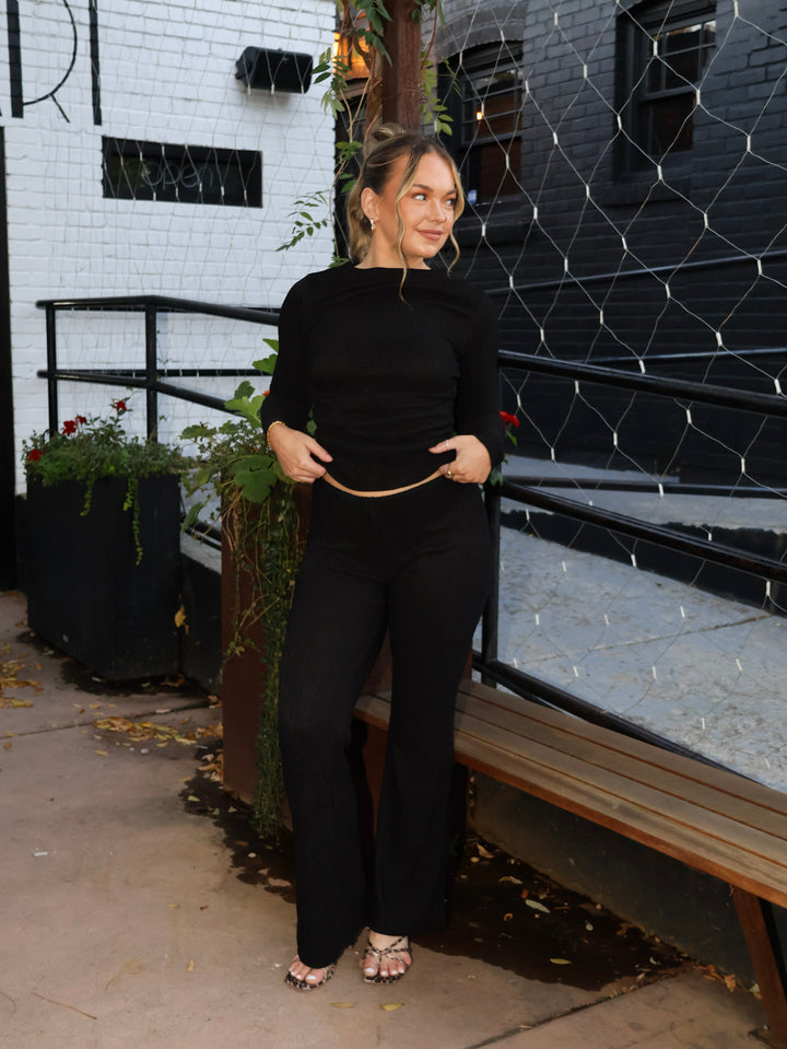 Woman in a black outfit standing in front of a black and white building.
