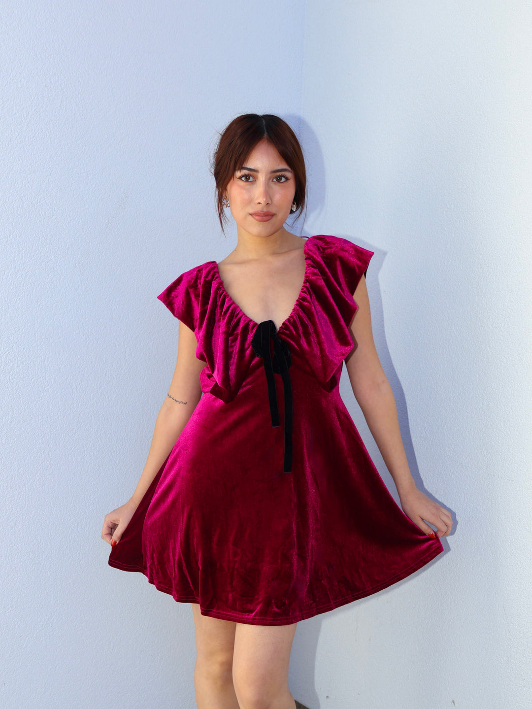 Woman wearing a burgundy dress with a bow detail against a light blue background