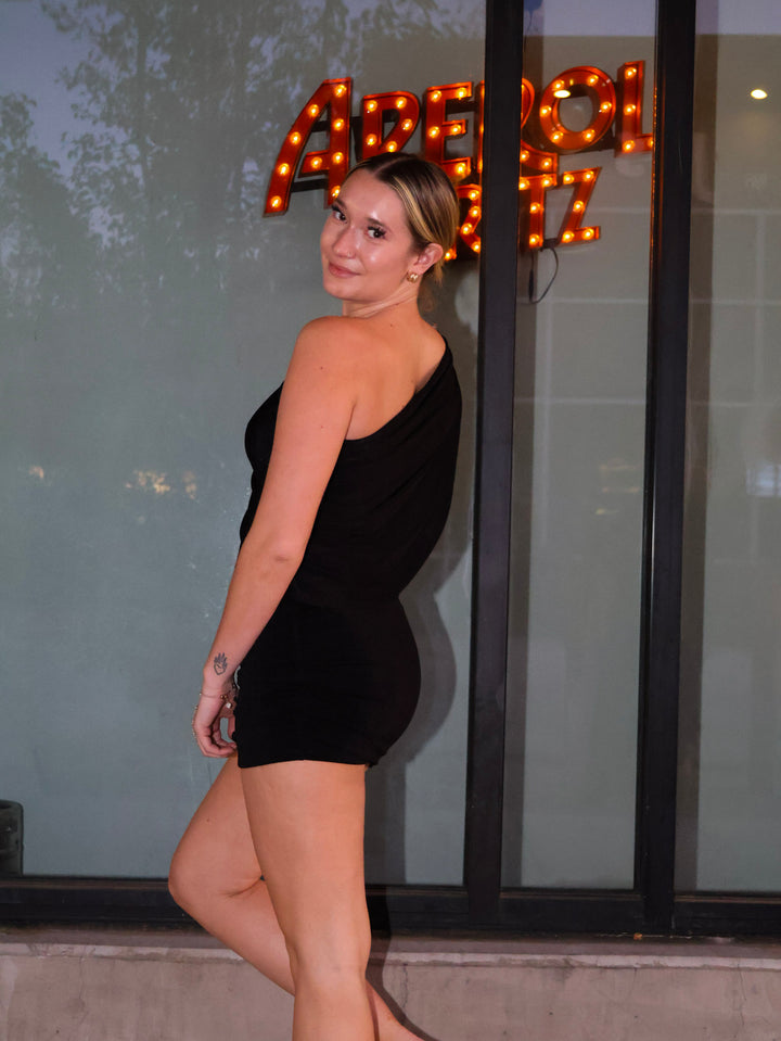 Woman in a black dress standing in front of a glass door with sign.