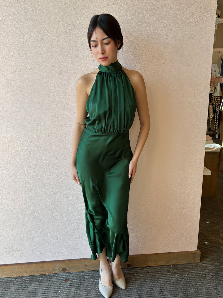 Woman wearing a green dress standing against a plain wall.