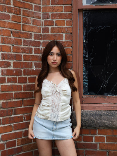 Woman standing against a brick wall with a window in the background