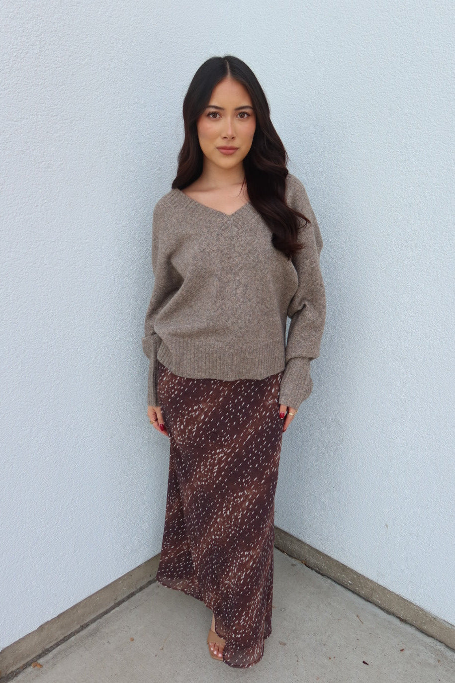 Model wearing the taupe Viloria V-neck oversized sweater with the burgundy print Bambi fluid maxi slip skirt, front view