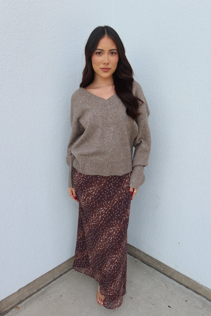 Model wearing the taupe Viloria V-neck oversized sweater with the burgundy print Bambi fluid maxi slip skirt, front view