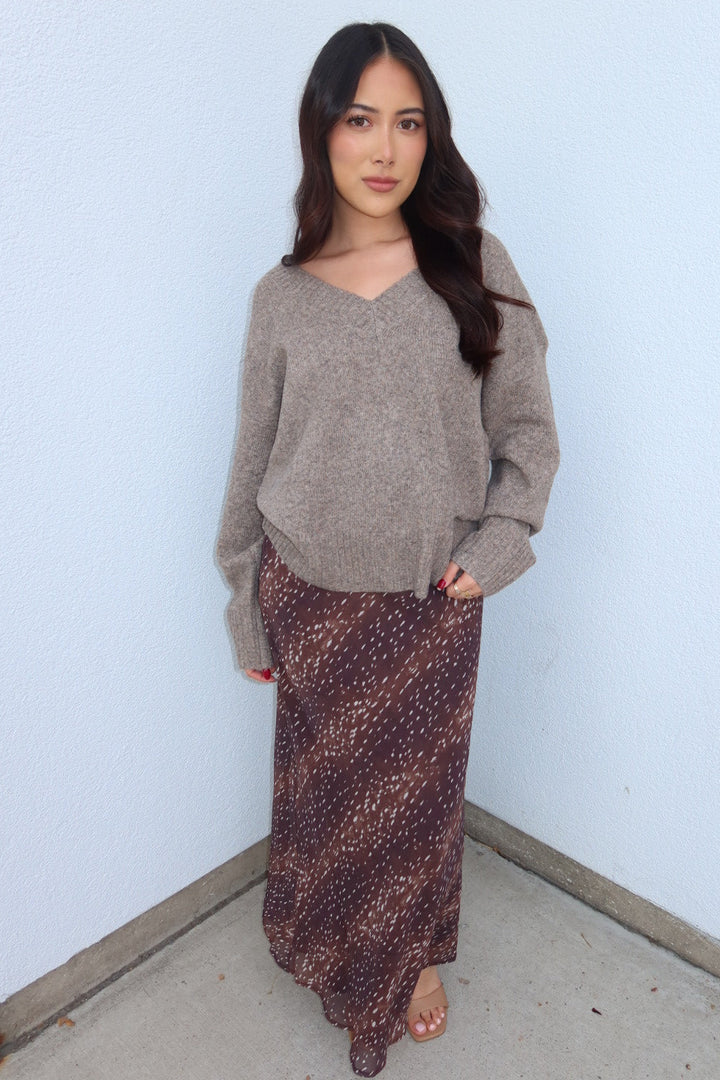 Model in the taupe Viloria V-neck sweater and burgundy print Bambi fluid maxi slip skirt, hands in pockets, front view