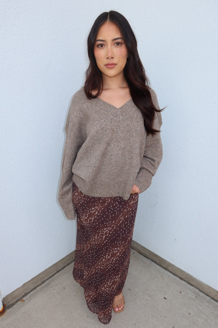 Model in the taupe Viloria V-neck oversized sweater with hands in her skirt pockets, front view