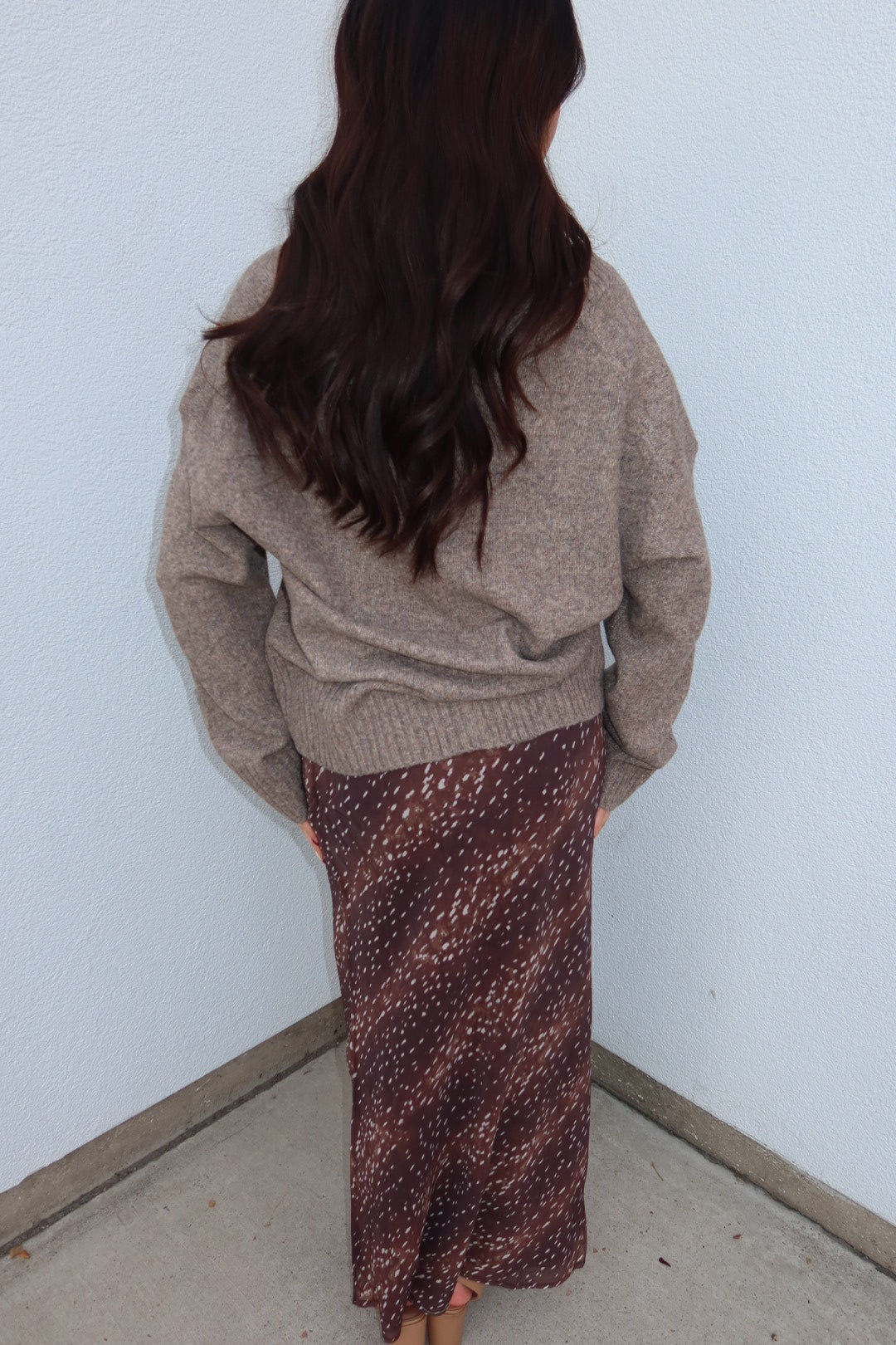 Back view of the burgundy print Bambi fluid maxi slip skirt with an oversized taupe sweater