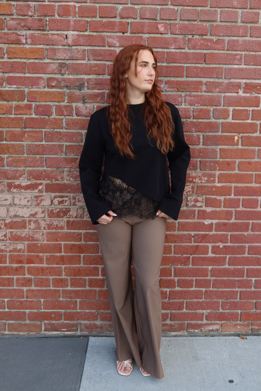 Model in the black Charlie asymmetric lace trim top and taupe Billie tailored wide leg trousers, hands in pockets, full length