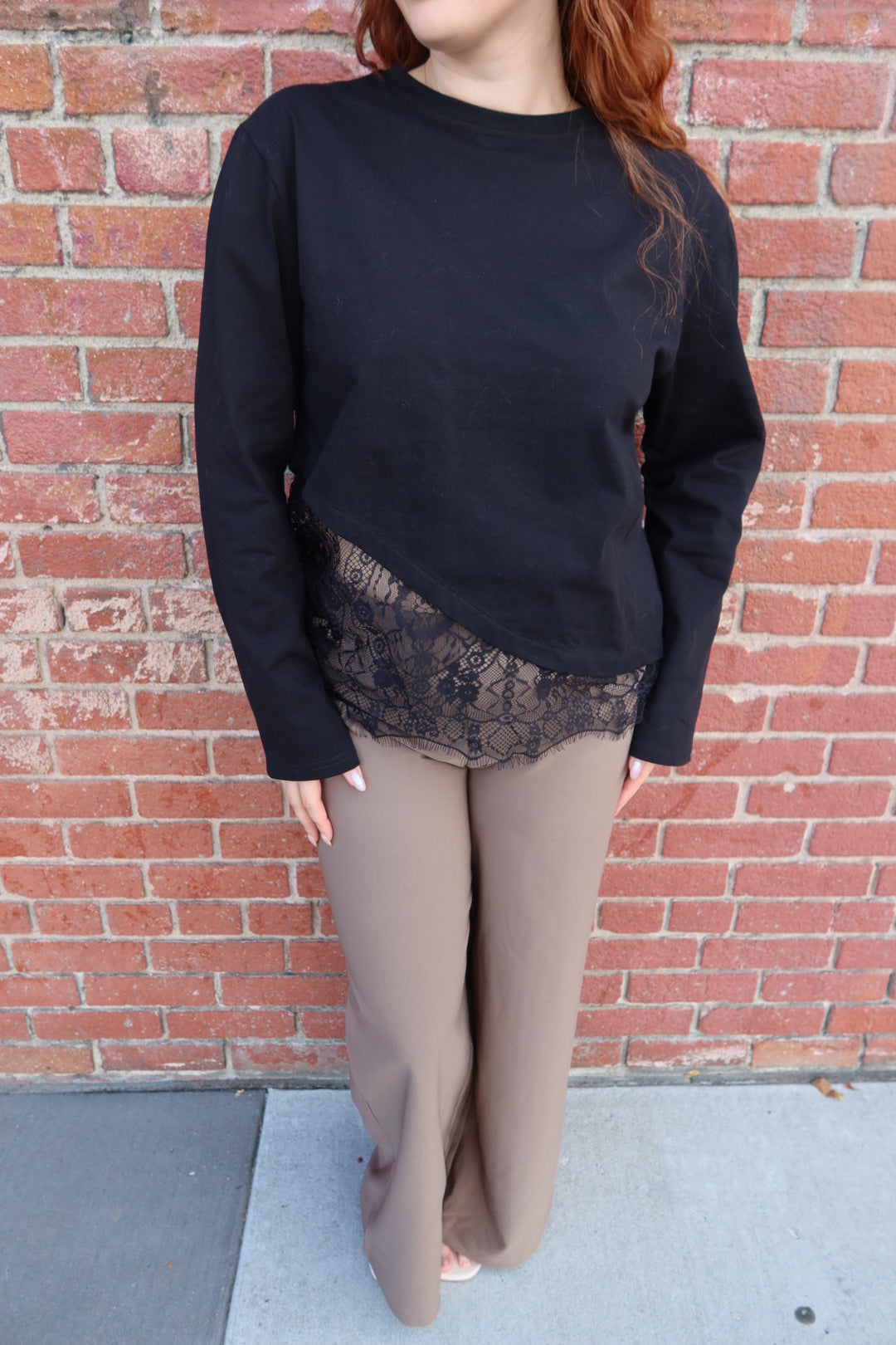 Front view of the black Charlie asymmetric lace trim top, showing the asymmetric lace trim, worn with taupe wide leg pants