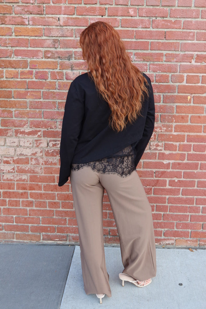 Angled back view of the black Charlie asymmetric lace trim top and taupe Billie tailored wide leg trousers