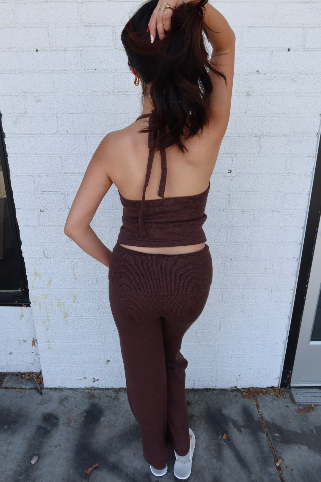 Back view of the brown Kelsey knit halter top and fold over trouser set, showing the open halter back and tie at the neck
