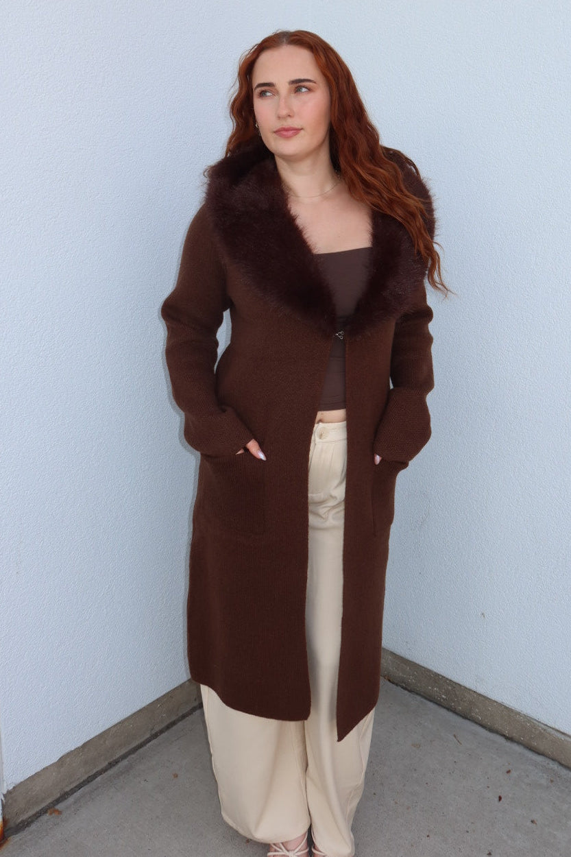 Model wearing the brown Felicity faux fur collar cardigan with hands in pockets, showing the plush collar and long length