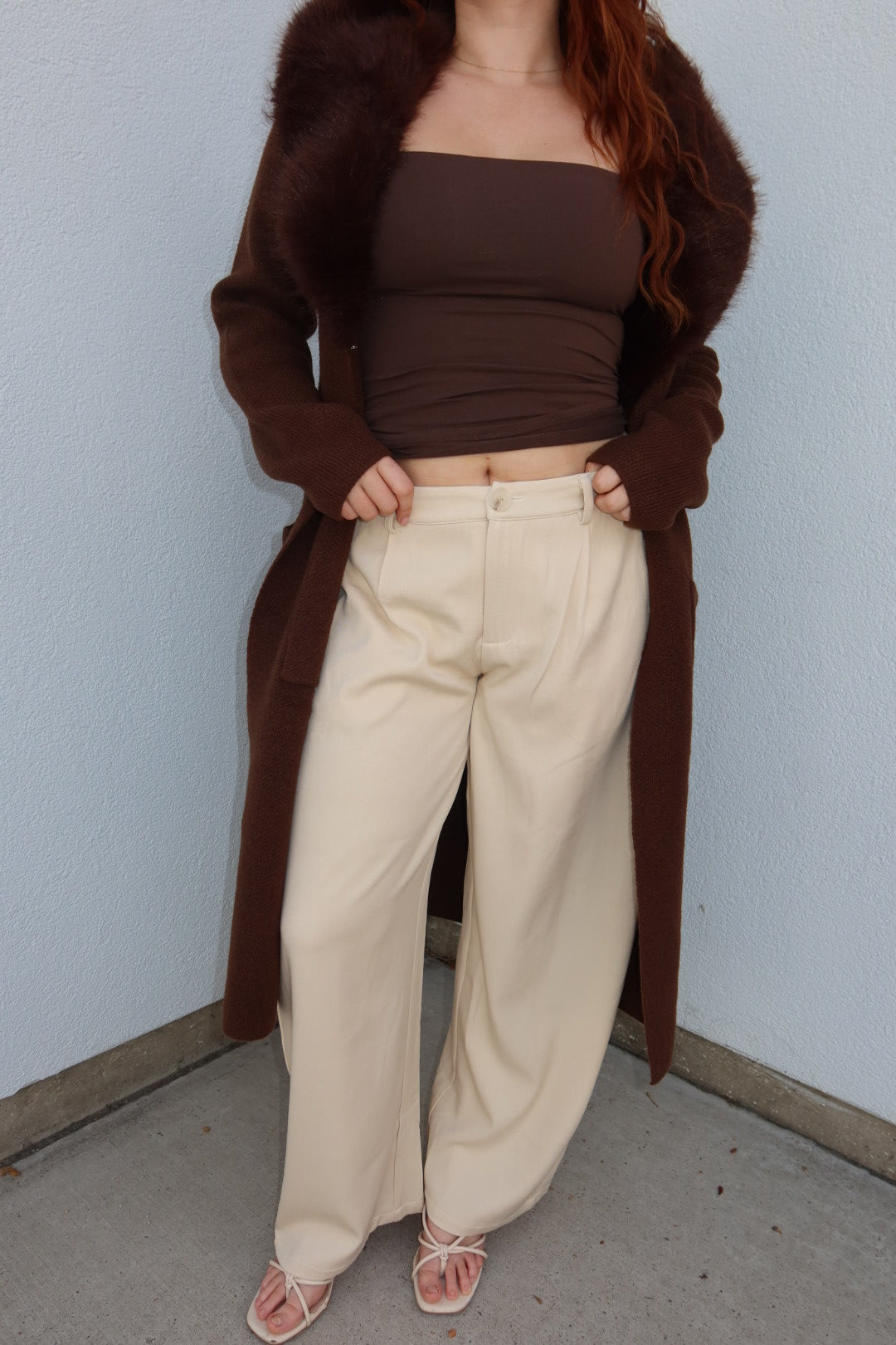 Model wearing the cream Louis pleated barrel wide leg pants with a brown tube top and long fur collar cardigan