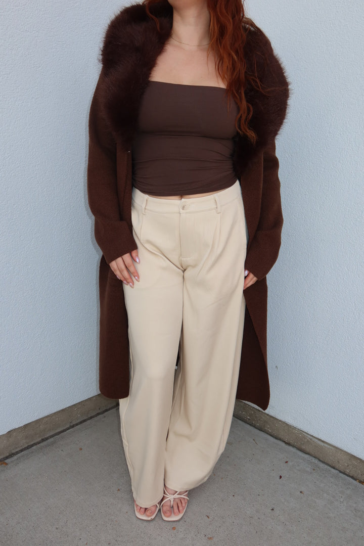 Model in the brown Felicity faux fur collar cardigan, open over the cream Louis pleated wide leg pants