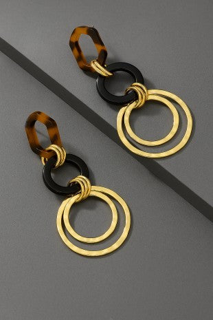 Gold and tortoiseshell hoop earrings on a gray background