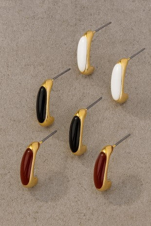 Set of earrings with gold, black, and red accents on a beige background